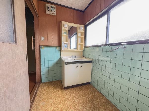 松岡　戸建ての独立洗面台|大きな窓があり自然光がたっぷり入る洗面所です。収納棚も備わっており小物の整理がしやすい設計です。落ち着いたタイルと木目調の壁が特徴的でレトロな雰囲気が漂います。
