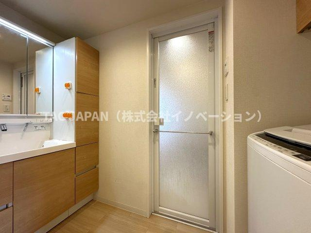 日神パレステージ東日暮里の洗面所|大型の洗濯機を置いても余裕が感じられる脱衣スペースにはお洒落な洗面ユニットを創作。着替えやタオル、洗剤の買い置きなどリネン庫の使い方はお客様しだい。つなぎ目が無くお手入れ楽々シームレス洗面ユニット。