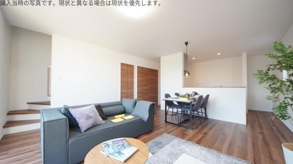 大字皆春　戸建ての居間・リビング|落ち着いた色合いのフローリングとシンプルなインテリアが特徴のリビングです。光がしっかり入る明るい空間となっています。ダイニングスペースとのつながりもスムーズで開放的な印象です。