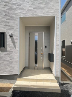 【玄関】 | 佐伯区八幡1丁目（全6棟）No5 | 雨の日でも鍵の開け閉めがしやすい、奥行きのあるインナーポーチ仕様の玄関。玄関ドアは中央に採光部を設けたデザインで、防犯性に配慮しつつ室内へ自然光を届けます。宅配ボックスも完備しています。