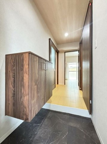 甲南第10兵庫コーポラスの玄関|高級感のある石目調の土間と木目調の天井が調和し、奥まで見通せる開放的な廊下がつづく玄関ホールです。