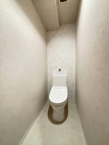 甲南第10兵庫コーポラスのトイレ|温水洗浄便座付きのトイレです。背面のデザインクロスや、小物が置ける棚付きのペーパーホルダーなど、細部までこだわりを感じる清潔な空間です。