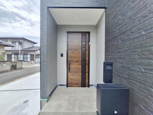 P-TELAS森町2の玄関|玄関ドアは重厚感のあるデザインで住まいの印象を引き締めます。タイル張りのアプローチは手入れがしやすくスムーズに出入りできる広さがあります。宅配ボックスも設置されており利便性に配慮されています。