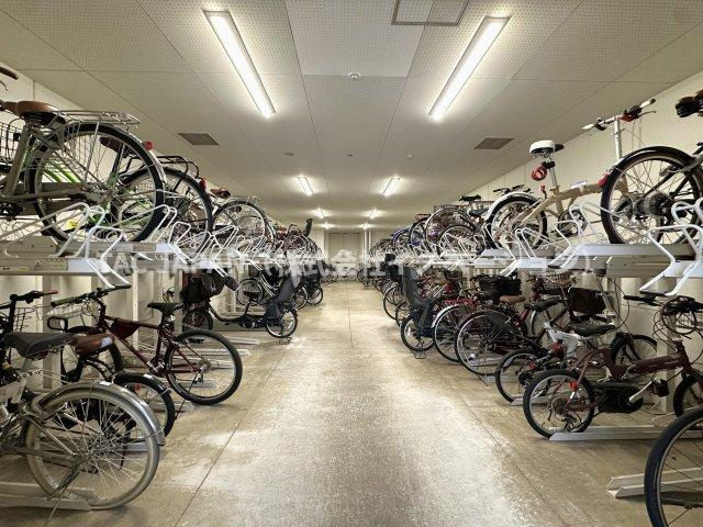 コートレジデントタワーの駐輪場|敷地内屋内に設置された駐輪場は月額200円／台でご利用いただけます。二段式ラックで多くの自転車を効率的に収納し、清潔で明るい空間に整然と保管。雨風や盗難の心配が少ない安心の管理体制です。