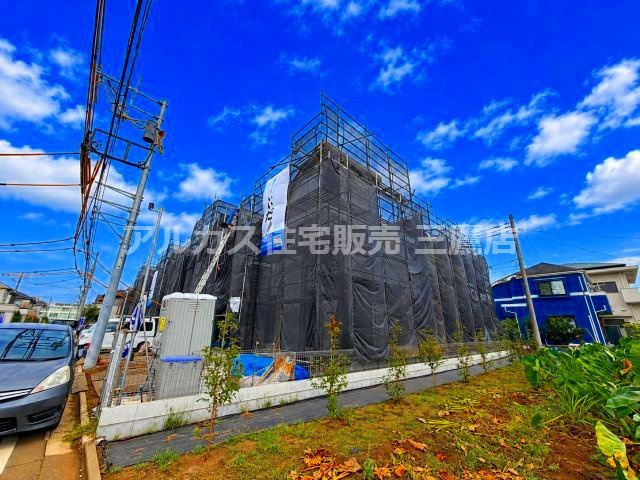 小平市鈴木町1丁目 西武新宿線 花小金井駅 売地の外観|青空のもと足場と養生シートに包まれた建築中の建物外観。前面道路から敷地へのアクセスもしやすく完成が心待ちにされる新築物件です。