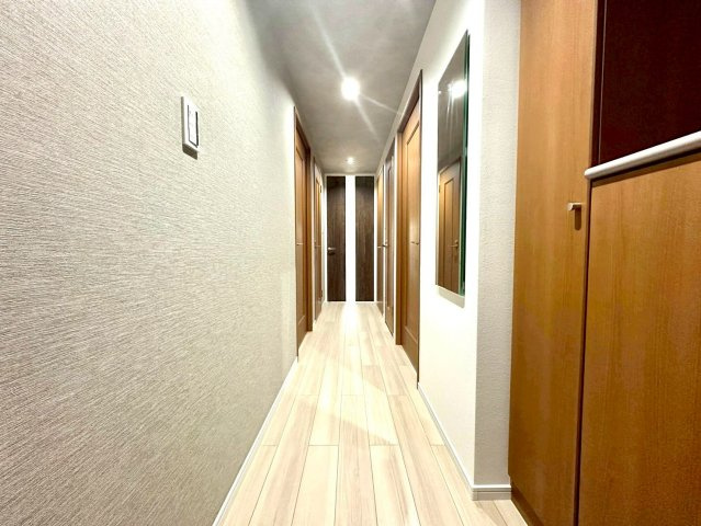 仲町台パークヒルズ五号棟の玄関|奥行きのある美しい玄関・廊下空間。木目の建具と柔らかな照明が調和し、上質で落ち着いた住まいの印象を演出します。