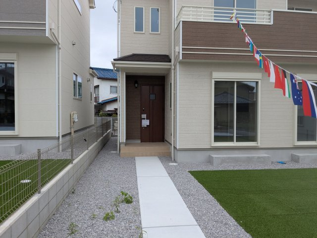 新築戸建　片岡町の駐車場|緑広がる人工芝のお庭と広々コンクリート駐車場。アプローチも整備され、快適なお庭空間です。