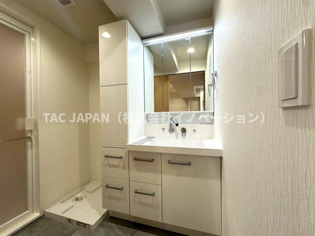 朝日江戸川橋マンションの洗面所|大型の洗濯機を置いても余裕が感じられる脱衣スペースにはお洒落な洗面ユニットを制作。着替えやタオル、洗剤の買い置きなどリネン庫の使い方はお客様しだい。
