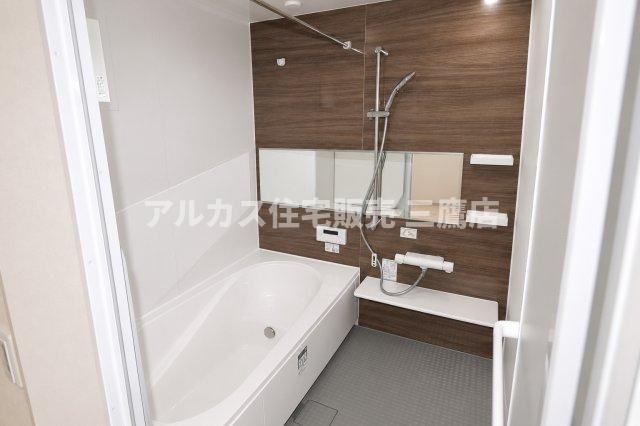小金井市貫井南町3丁目 中央線 武蔵小金井駅 新築戸建の浴室|木目調パネルが落ち着きを添える浴室。横長ミラーと浴室物干しバーを備え、使い勝手にも配慮されています。
