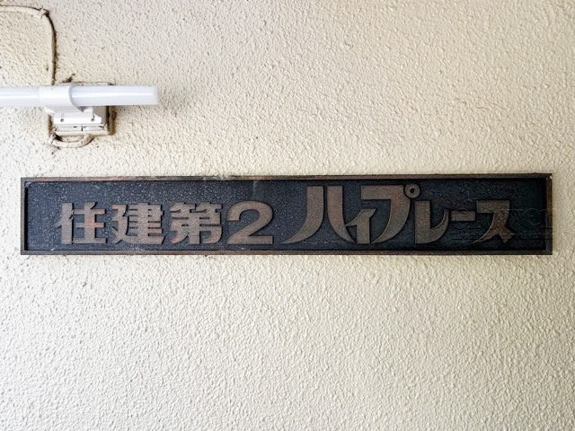 【現況写真】 | 住建第二ハイプレース | エントランスに掲げられた、マンション名を示す館銘板。さほど激しく主張はしませんが、しっかりと掲示されています。～即日のご見学可能～　お問合せはお気軽にどうぞ。