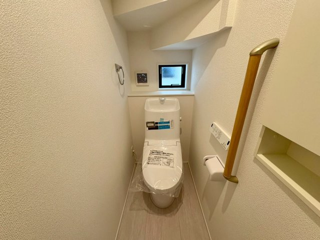 【残り1棟】高知市福井東町3期2棟　1号棟新築戸建てのトイレ|階段下を賢く活用したトイレ。窓付きで換気も良好、手すりや埋込収納も備えた安心・便利な設計です。