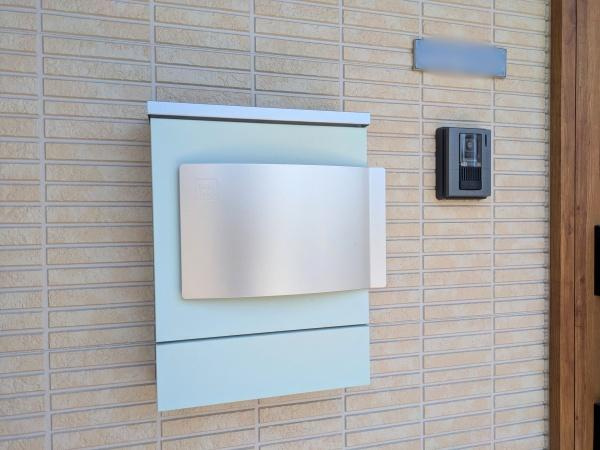 大字江無田　戸建ての内装|シンプルなデザインのポストが外観に調和しています。インターホンや表札も近くに揃い使い勝手に配慮されています。郵便物の取り出しもしやすい配置です。外壁の質感とポストの色味が統一感を演出しています。