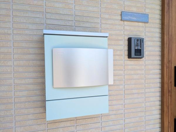 大字江無田　戸建ての内装|シンプルなデザインのポストが外観に調和しています。インターホンや表札も近くに揃い使い勝手に配慮されています。郵便物の取り出しもしやすい配置です。外壁の質感とポストの色味が統一感を演出しています。
