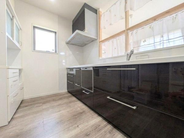 大字江無田　戸建てのキッチン|落ち着いた色合いのキッチンはスッキリとした印象です。大きめの窓から自然光が入り全体的に明るい空間です。広々としたカウンターは使い勝手も良好です。収納スペースも充実しており整理整頓がしやすい構造です。