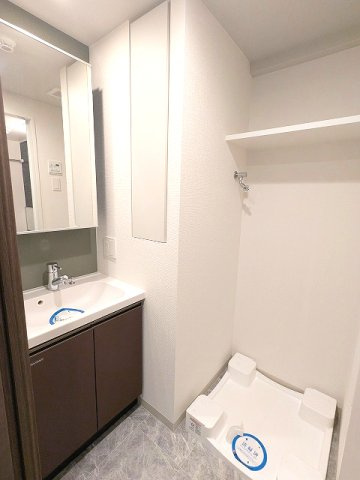 Renaissance Court浅草の洗面所|トイレと独立した洗面室、ハンドシャワー付、鏡の後ろに収納付、洗面室の洗濯機置場は排水溝のお手入れがし易い様に中央手前に配置し、足高の防水パンです