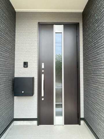 今治市別宮町第1-2号棟　新築戸建の玄関|TVモニタ付インターホンで、来客時も室内から確認できて安心。段差の少ない設計は、重い荷物を持っての帰宅もスムーズに。清潔感のある扉を開けるたびに、新しい生活への期待と喜びが家族を優しく迎えてくれる。