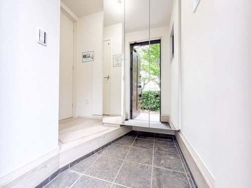【FIT】小平市中島町２期の玄関|白を基調とした内装に、窓からの自然光が差し込む明るい設計。
家族やゲストを優しく迎え入れる、家の「顔」にふさわしい空間です。
