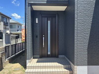 【玄関】 | 【リフォーム住宅】中古一戸建　玉島上成　4LDK+S | 玄関扉も新品になり、スタイリッシュな雰囲気に生まれ変わっています。
玄関はポーチ屋根もしっかりとあるので、雨の日のお出かけも安心♪