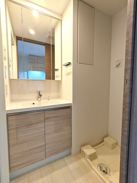 ヴィークブライト蔵前の洗面所|トイレと独立した洗面脱衣室、三面鏡付ハンドシャワー付洗面台、洗濯機置場の排水口はお手入れしやすい様に手前中央に配置し、足高の防水パンです