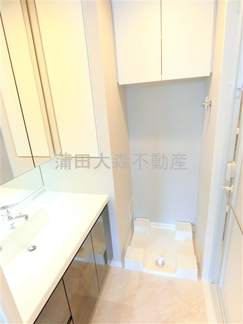 シーズンフラッツ蒲田の洗面所|3面鏡の独立洗面台と棚付きの洗濯機置き場　洗面脱衣所　