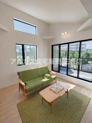 府中市幸町1丁目　京王線　府中駅　新築戸建の居間・リビング|高窓と大きな掃き出し窓から豊かな自然光が差し込むリビングスペース。勾配天井による解放感と、落ち着いたインテリアが魅力です。