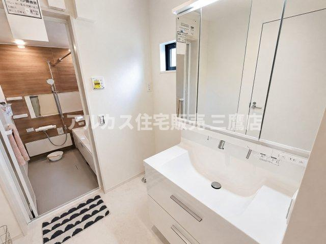 府中市幸町1丁目　京王線　府中駅　新築戸建の洗面所|三面鏡洗面台を備えた清潔感のある洗面脱衣室。奥には浴室が続き、スムーズな家事・入浴動線が確保されています。