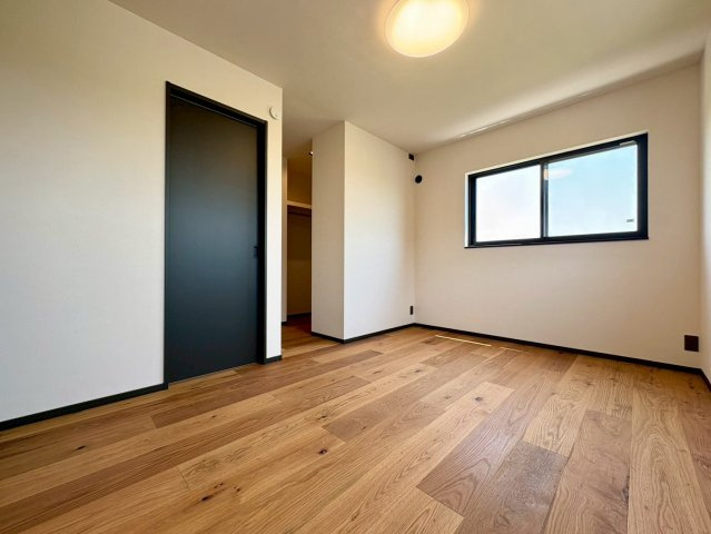 「サウナ付き分譲住宅」南国市大そね甲2号地　新築一戸建ての洋室|落ち着いたフローリングと黒の建具がモダンな主寝室。奥には便利なウォークインクローゼットも完備。