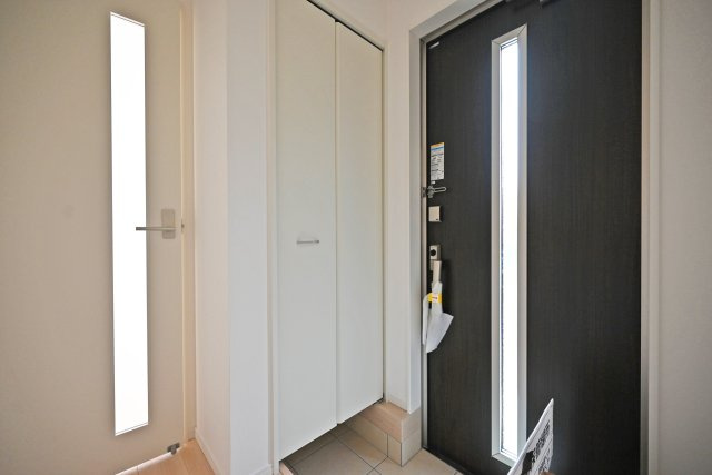 クレイドルガーデン山田3丁目新築一戸建て│4LDK+駐車駐輪の玄関|1階玄関を廊下側から撮影した内観写真です。 収納庫内は可動棚になっているので靴のサイズに合わせて棚の高さを変更できます。