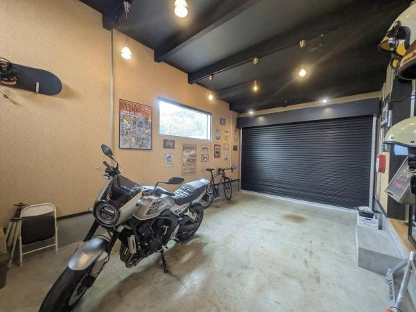 久原南2丁目　戸建て(美容室併設)の駐車場|広々とした駐車場はシャッター付きで愛車を安心して保管できます。天井のダウンライトが明るさを確保し室内空間が快適な印象です。壁にはポスターや装飾が施され個性を感じるスペースとなっています。