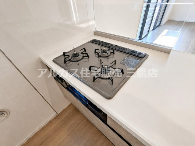 府中市南町2丁目　京王線　分倍河原駅　新築戸建のキッチン|手入れのしやすい天板を備えた3口ガスコンロです。油はねを防ぐガラスパネルやグリルが付いており、毎日の調理に役立ちます。