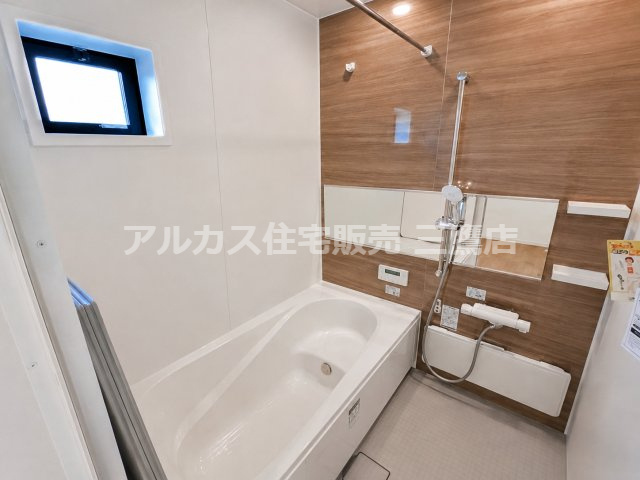 府中市南町2丁目　京王線　分倍河原駅　新築戸建の浴室|ゆったりと入浴できる浴槽とシャワーフックを備えた浴室空間です。カウンターやラック、小窓が付いており、バス用品をすっきりと整理できます。