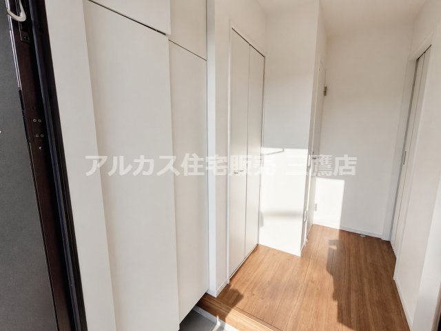 府中市南町2丁目　京王線　分倍河原駅　新築戸建の玄関|木目調フローリングと白い壁面が温もりを演出する玄関ホールです。トールサイズのシューズボックスや扉付きの収納スペースを備えています。