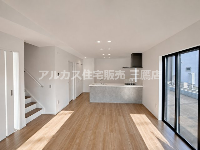 府中市南町2丁目　京王線　分倍河原駅　新築戸建の居間・リビング|対面キッチンとリビング階段を備えた開放的なLDK空間です。木目調の床と白い壁面が優しく調和し、大きな掃き出し窓から明るい光が差し込みます。