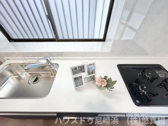 中古テラスハウス　西宮市樋ノ口町２丁目のキッチン|三口コンロとグリルでの同時調理で時短＆効率アップ♪キッチン前に窓があり、お料理中の換気もバッチリ♪