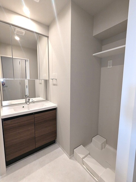 Opus Residence上野元浅草の洗面所|三面鏡付・ハンドシャワー付の独立洗面台、室内洗濯機置場、御手入れし易く排水口を手前中央に配置し、足高の防水パンです