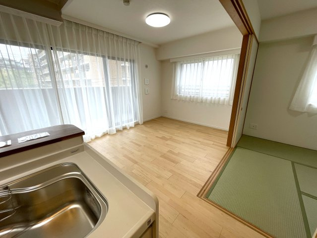 玄関ポーチがあるコトによってプライバシー得やすい角部屋に。オープンタイプの和室も使い勝手が良さそうで、うたた寝注意の『ナイスサンソレイユ横濱鶴ヶ峰』リノベーションの居間・リビング|ゆったりとした居間です