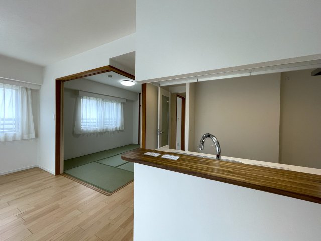 玄関ポーチがあるコトによってプライバシー得やすい角部屋に。オープンタイプの和室も使い勝手が良さそうで、うたた寝注意の『ナイスサンソレイユ横濱鶴ヶ峰』リノベーションの居間・リビング|ゆったりとした居間です