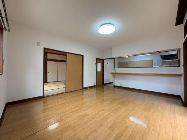 鎌倉市植木の中古一戸建の居間・リビング|広々としたリビングは木目調のフローリングが空間を上品に演出します。大きな窓からの明るい光が部屋全体に広がります。カウンター付きのキッチンが隣接しており開放感のある造りが特徴です。