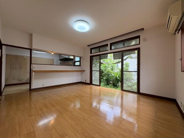 鎌倉市植木の中古一戸建の居間・リビング|リビングは大きな窓が特徴で自然光がたっぷり入ります。木目調のフローリングがすっきりとした印象を与えます。カウンター越しにキッチンが見える開放的な空間です。室内はエアコン設置済みで快適に過ごせます。