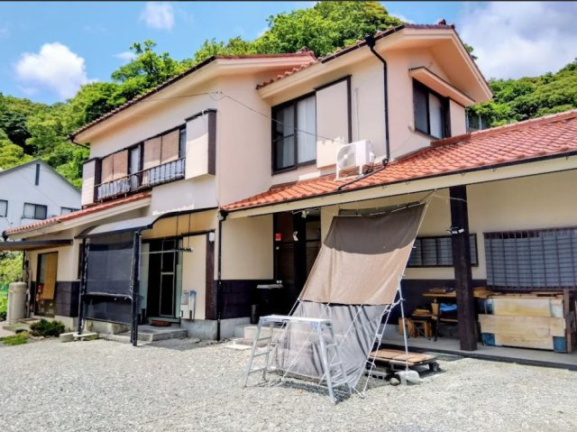 売中古戸建　伊豆市土肥の前面道路含む現地写真|車の出し入れがしやすい平坦な砂利敷の前面スペ－スを備えた一軒家です。周囲の自然に調和する落ち着いた佇まいが魅力の物件です。
