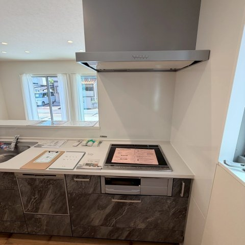 空港通７丁目　新築戸建　3LDKのキッチン|機能的で使いやすいシステムキッチンは、食器洗乾燥機や浄水器が備わっており対面式を採用しているため、お料理中もリビングの家族と会話を楽しみながら毎日のお料理を軽やかな気分で楽しくこなせる。