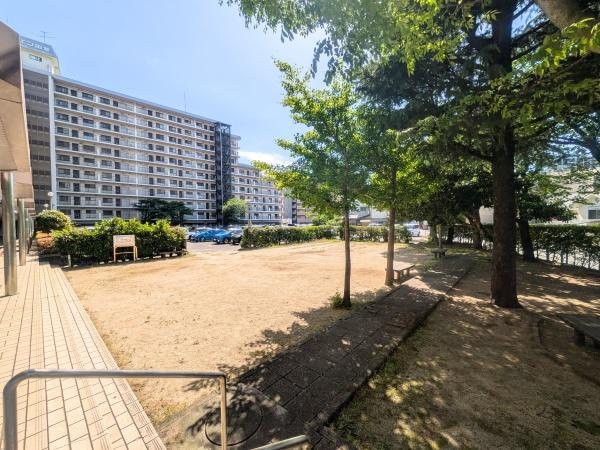 アーバン田室第二期棟のその他共用部分|敷地内に広々とした広場があり開放感のある空間です。日当たりも良好で快適に過ごせます。植栽や木陰もあり季節の変化を感じられる点も魅力です。マンションと広場の距離感も程よく安心感があります。