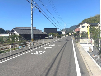 【前面道路含む現地写真】 | 廿日市市大野下更地（全3区画）No1 | 物件に面した前面道路は、見通しが良く平坦なアスファルト舗装となっています。「通学路」の標示があり、小さなお子様のいるご家庭にも配慮された周辺環境です。