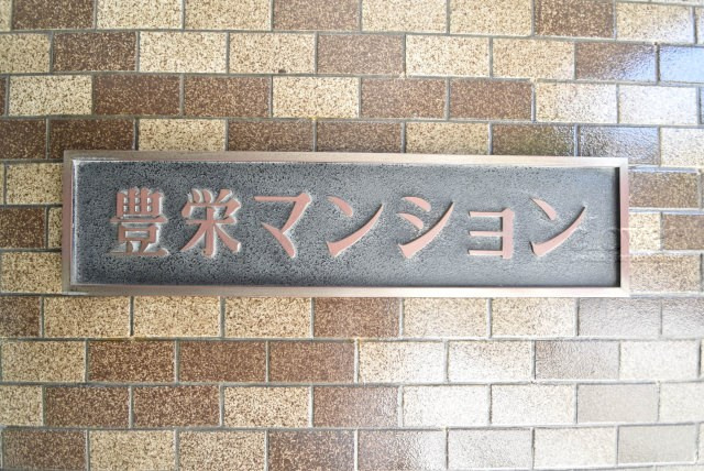 【現況写真】 | 豊栄マンション | エントランスに掲げられた、マンション名を示す館銘板。さほど激しく主張はしませんが、しっかりと掲示されています。～即日のご見学可能～　お問合せはお気軽にどうぞ。