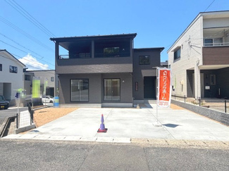 【外観】 | 佐伯区美鈴が丘南4丁目【全1棟】 | 落ち着いた色調の現代的な外観デザイン。前面には複数台駐車可能な土間コンクリート敷きのカースペースを確保しています。南側道路に面し、2階には広々としたインナーバルコニーが設けられ、日当たりも良好です。