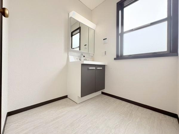 横浜市金沢区富岡東６丁目の中古一戸建の独立洗面台|明るい光が差し込む洗面所は清潔感のある内装で日々の身支度を快適にサポートします。シンプルなデザインの洗面台は収納スペースも充実しています。窓付きのため自然換気がしやすい点も魅力です。