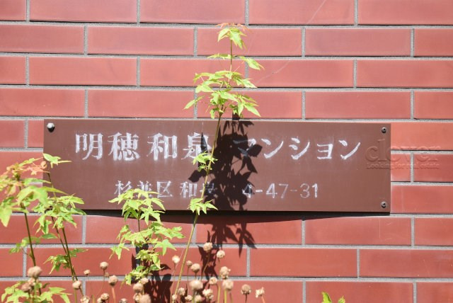【現況写真】 | 明穂和泉マンション | エントランスに掲げられた、マンション名を示す館銘板。さほど激しく主張はしませんが、しっかりと掲示されています。～即日のご見学可能～　お問合せはお気軽にどうぞ。