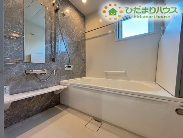 深谷市岡里　第2期　新築一戸建て　クライン　01の浴室|高級感あふれる壁面パネルが素敵なバスルームです！足を伸ばしてゆったりお湯に浸かれる広い浴槽で、一日の疲れを癒やしていただけます！手すりや小窓も付いており、安心・衛生的な空間です♪