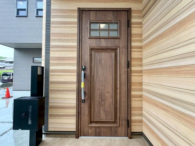 「LDK18帖」高知市大津甲2号棟　新築一戸建ての玄関|木目調のデザインが温かみを感じさせる玄関ドア。防犯面にも配慮されたしっかりとした造りで安心です。