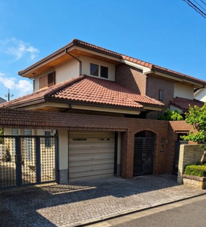 【外観】 | あすみが丘〈圧巻の199坪〉中古戸建　JR「土気」駅 | 温かみのあるオレンジ系の瓦屋根と、重厚感漂うレンガ調の外壁が美しく調和しています。シャッター付きの堅牢なガレージや、門扉を設けた格調高い佇まいが魅力です。